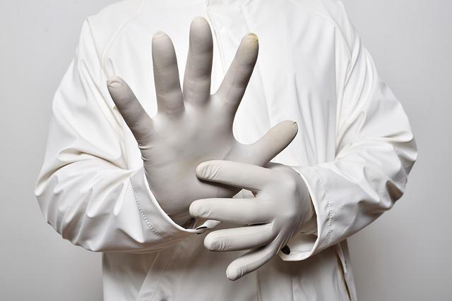 Lekarz zakłąda białe rękawiczi na dłonie